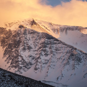 The setting sun casts a orange glow over a peak