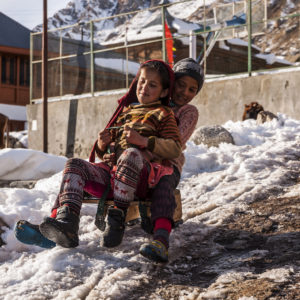 A brother and sister slide down on a sledge